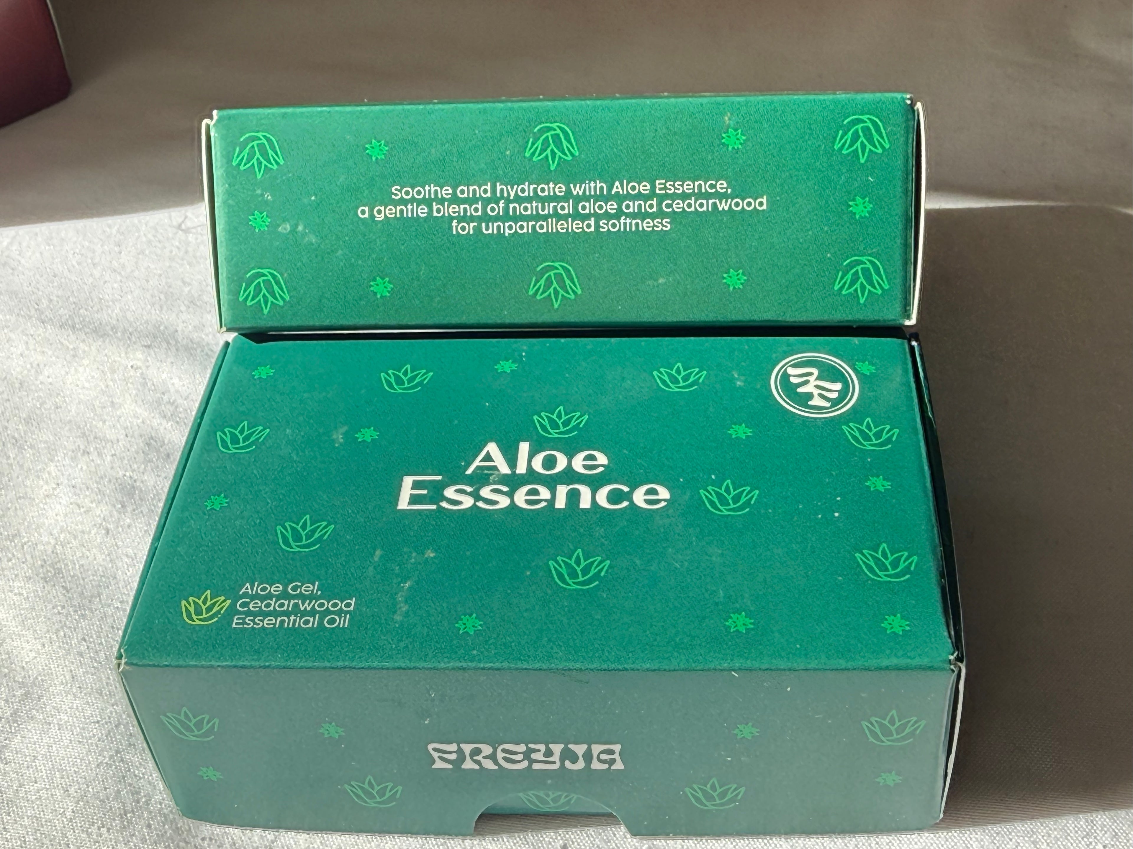 Green box labeled 'Aloe Essence' with branding on a neutral background