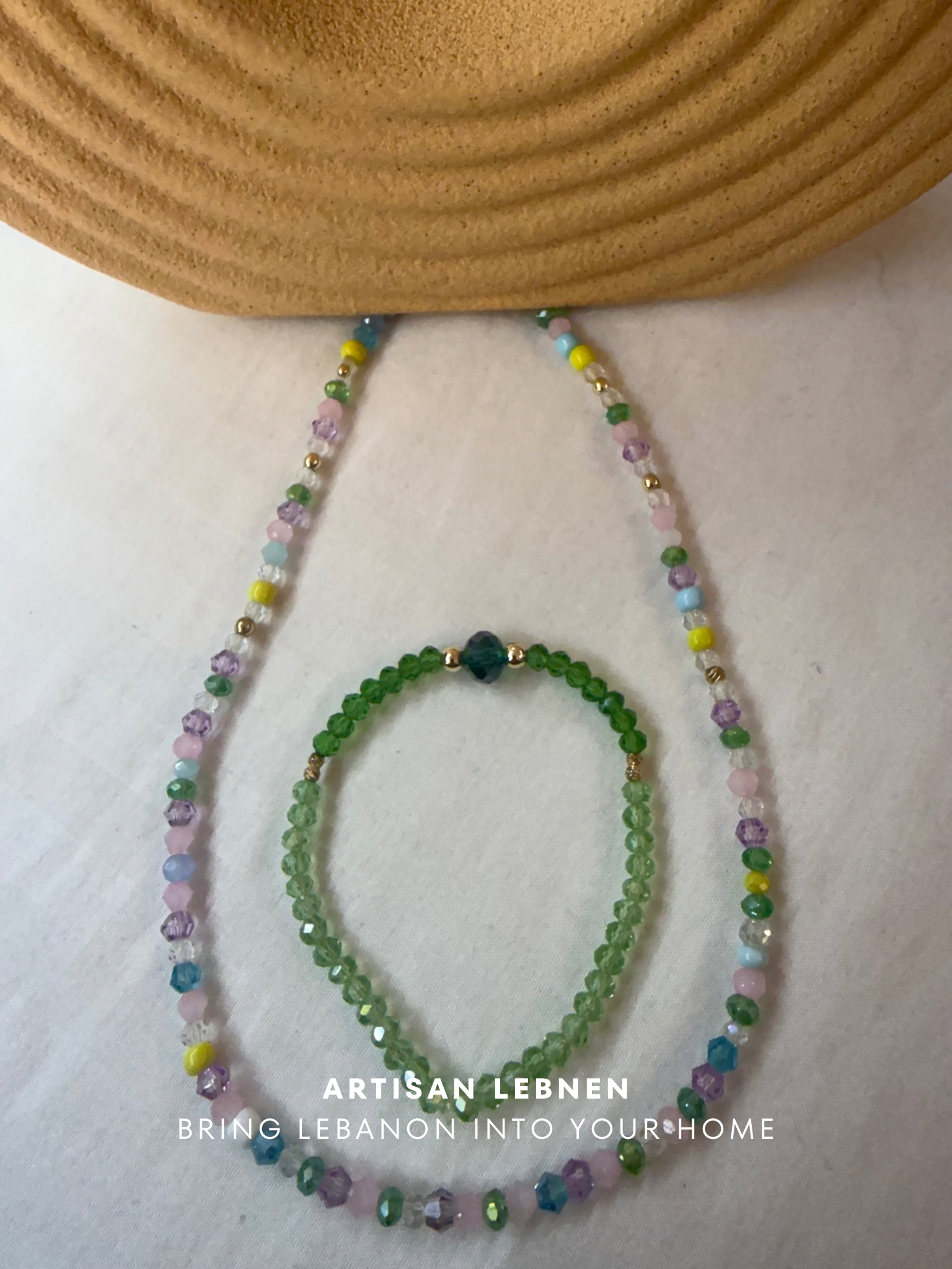Two beaded necklaces on a textured surface with 'Artisan Lebnen ' branding.