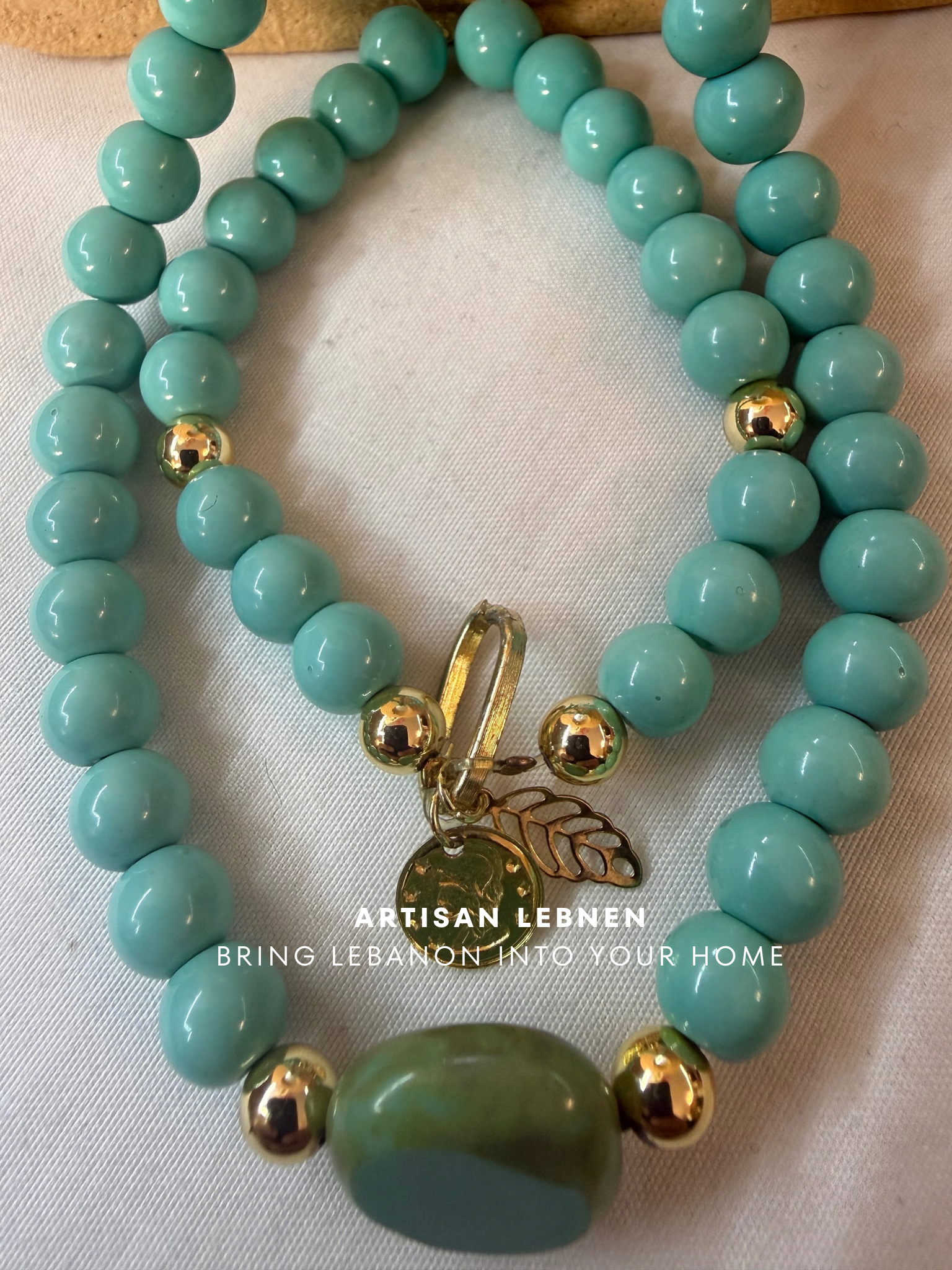 Turquoise beaded bracelet with gold accents and a tag on a light background