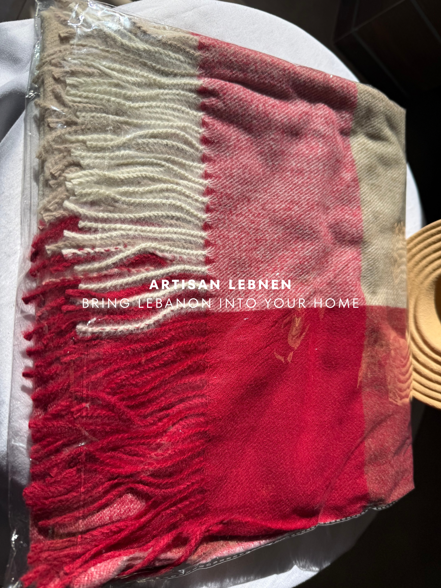 Red and beige plaid blanket with fringes on a white surface, featuring 'Artisan Lebnen' branding.