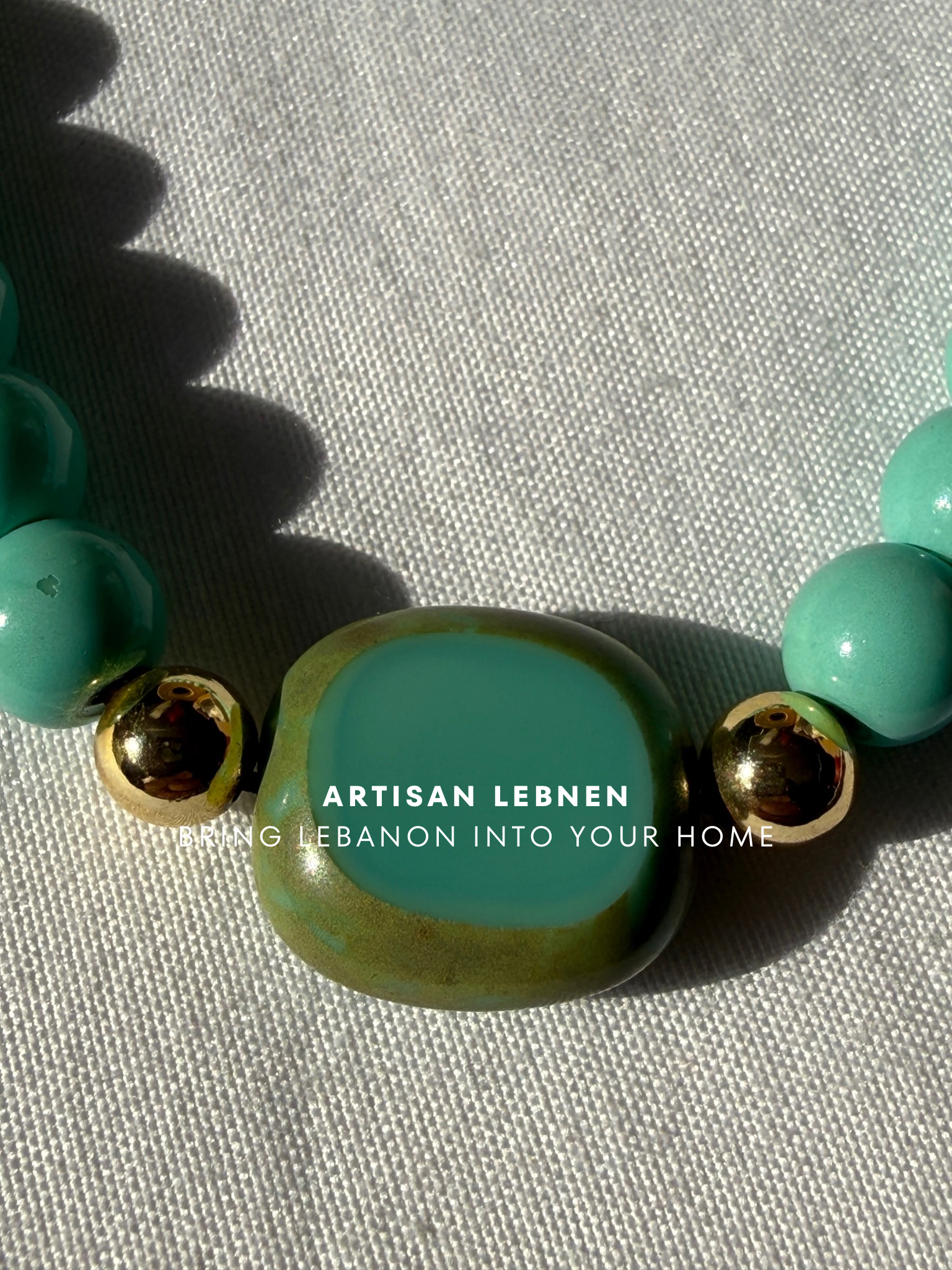 Turquoise beaded bracelet with gold accents on a light gray background, featuring 'Artisan Lebnen' branding.